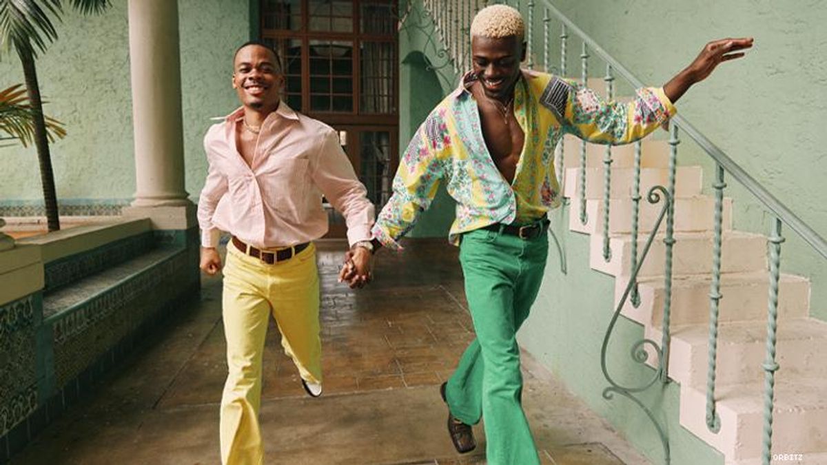 A colorfully dress black gay couple run hand-in-hand