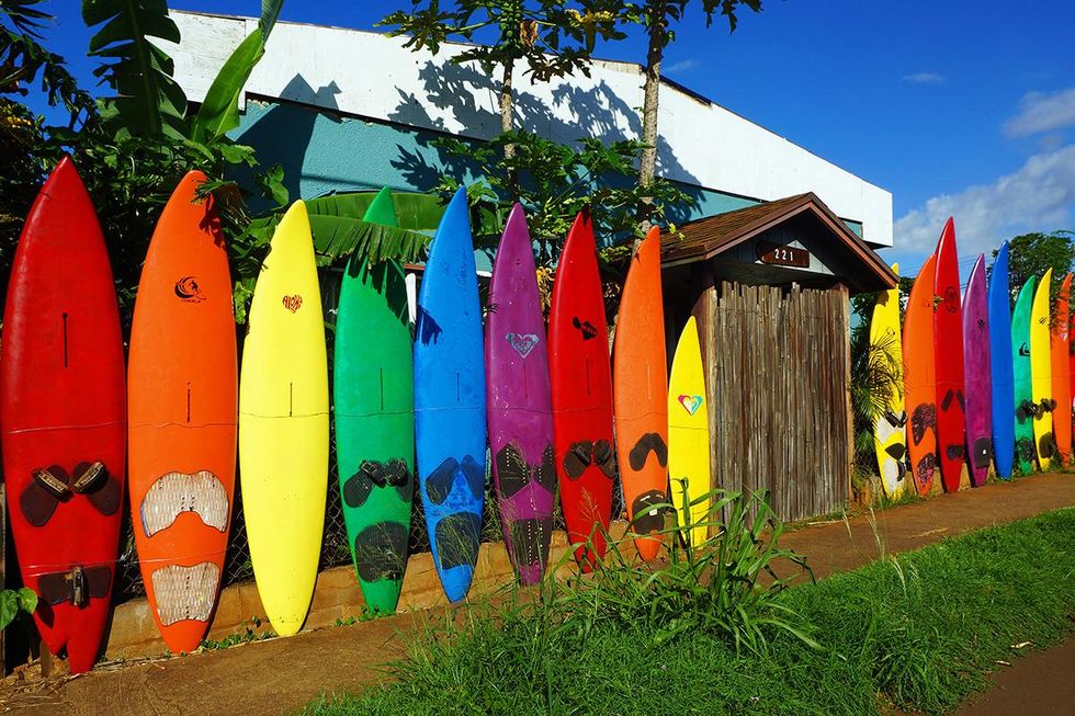 A fence made with a rainbow of used surfboards