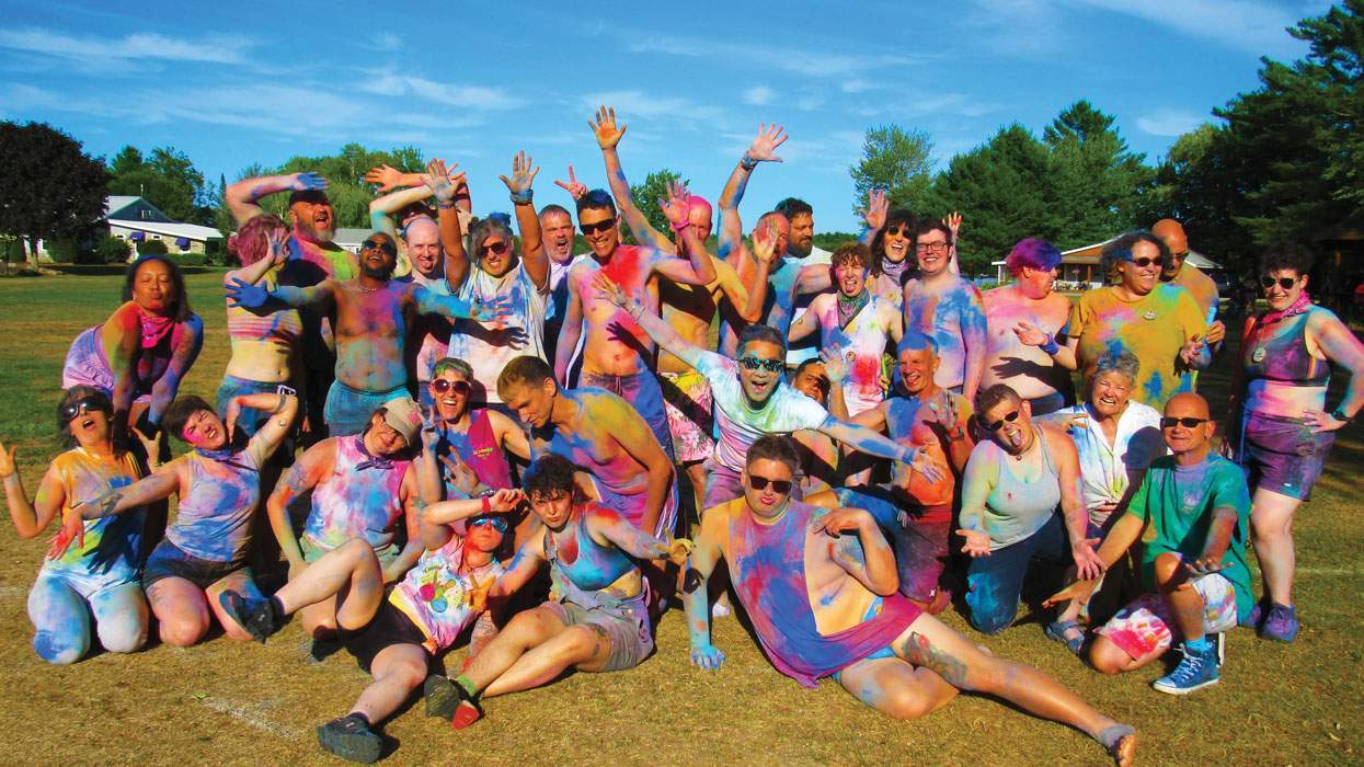 a group of people pose for a pic at an lgbtq summer camp after a game of color wars