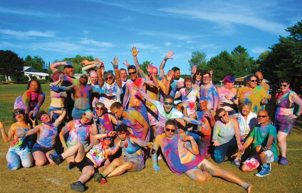 a group of people pose for a pic at an lgbtq summer camp after a game of color wars