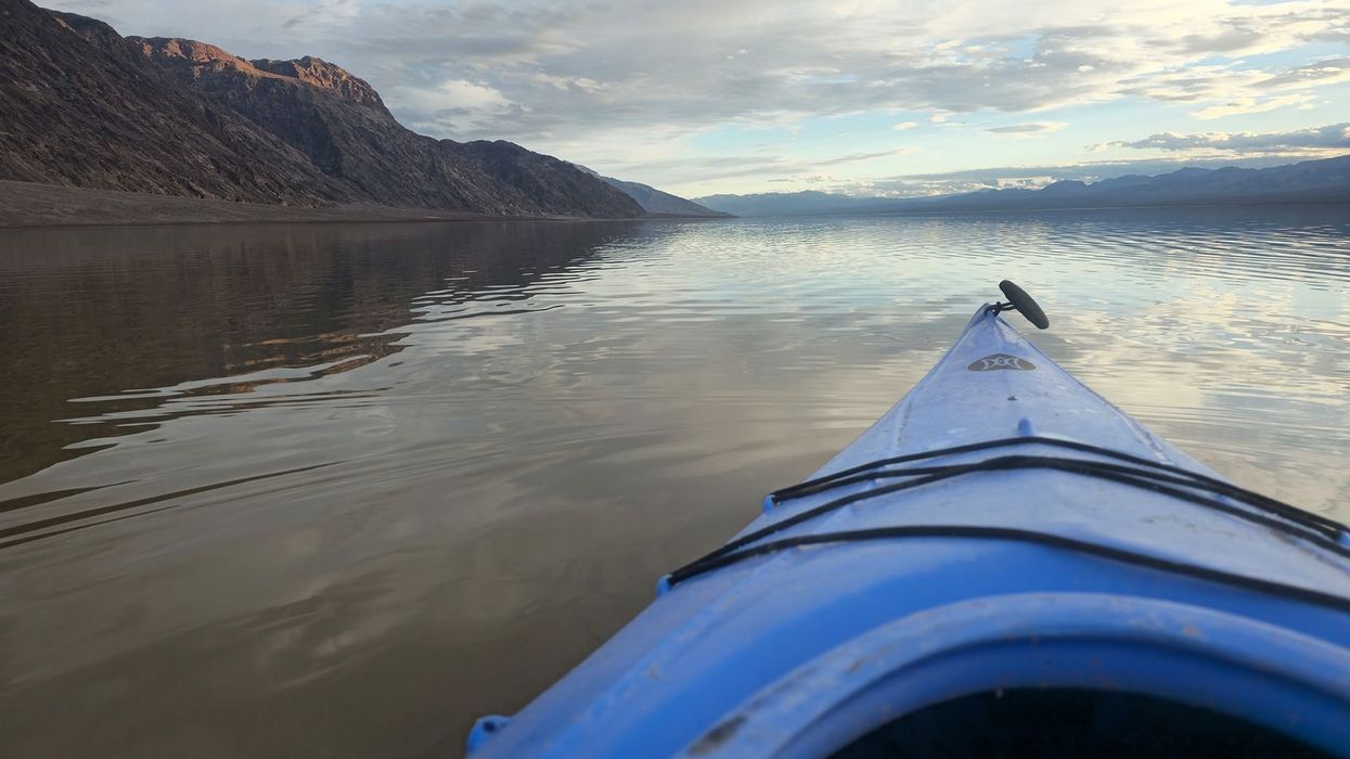 A kayaker on the temporarily filled Lake Manley in Death Valley National Park. Recent rains and flooding created the temporary water body which is six miles long, three miles wide, and only one foot deep