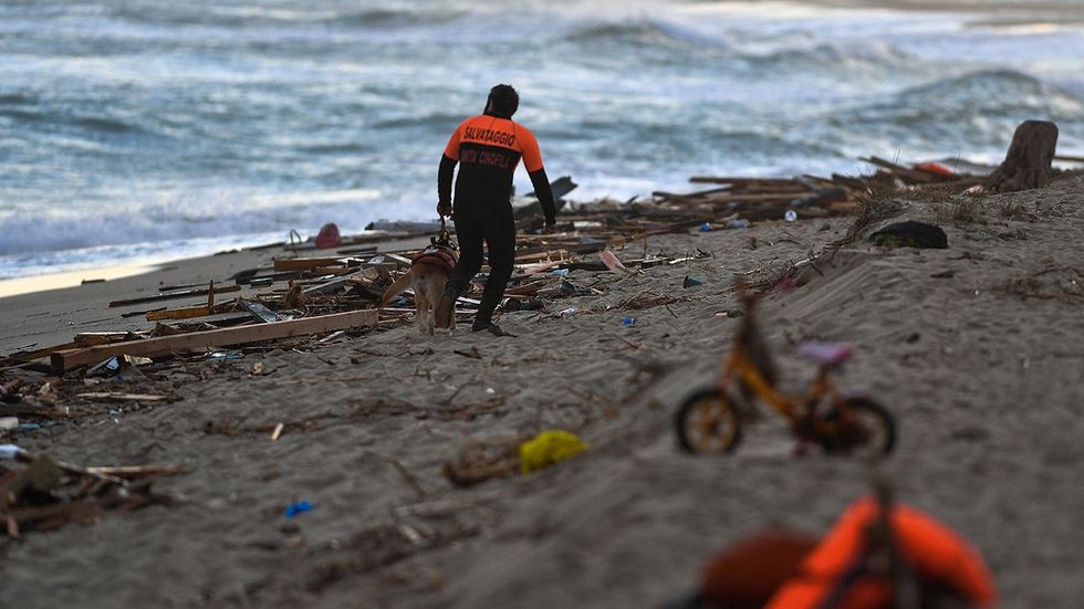 A rescuer scours the beach after a shipwreck that left mostly dead migrant children washing ashore