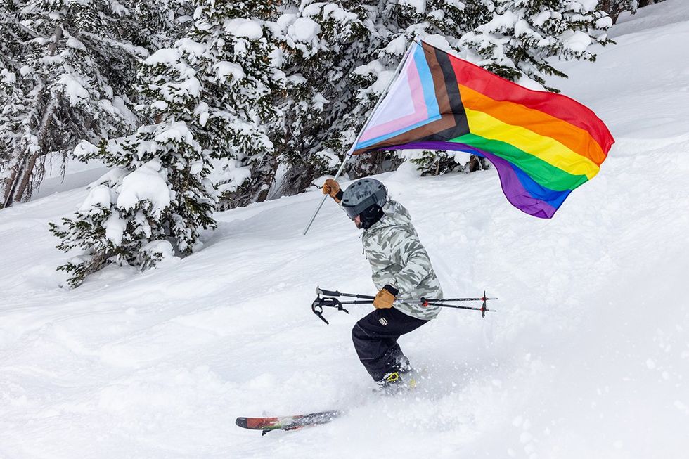 A skier with a pride flag skis down the slopes in Aspen and Snowmass