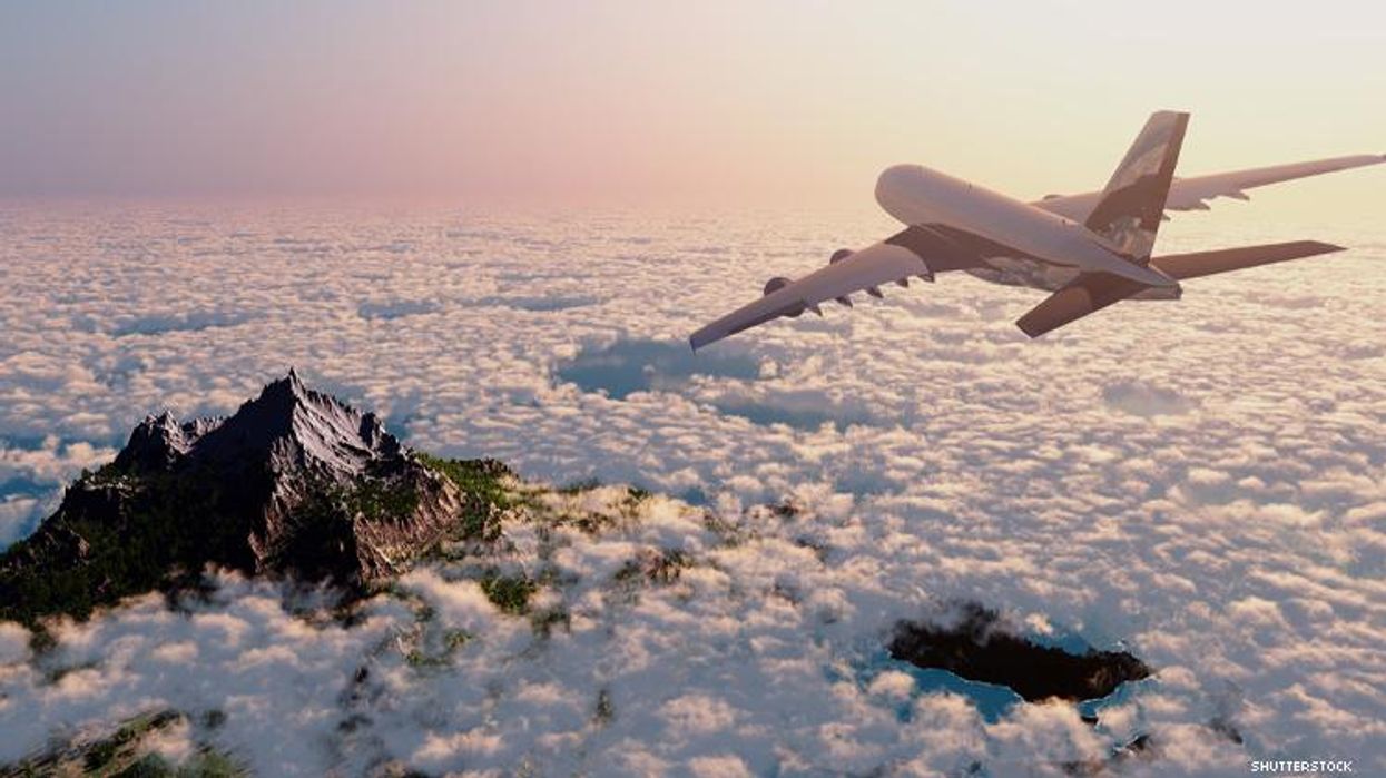 Airplane soars above the clouds and a mountain peak