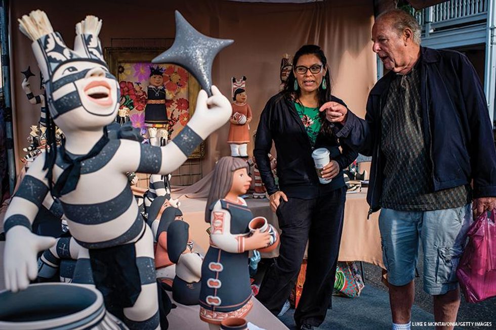 Artist Kathleen Wall, of the Jemez Pueblo of New Mexico, speaks with a customer during the 98th annual Santa Fe Indian Market. It hosts 1,200 Native American artists and draws crowds of up to 150,000 annually