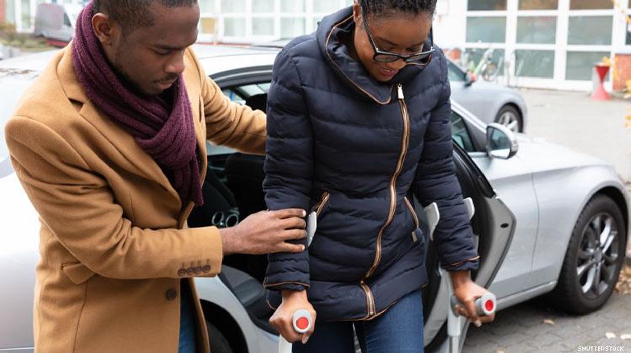 Black man helps a disabled Black woman out of car