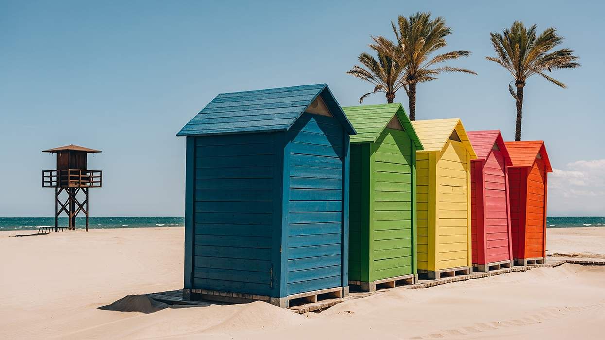 colorful row beach bungalows with lifeguard stand and palm trees