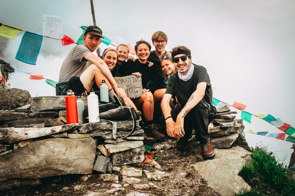 group picture of men and women on hill at daytime