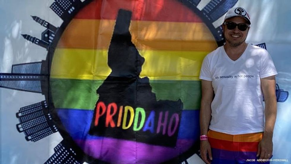 Jacob Anderson-Minshall at Pocatello Pride 2021 in front of Priidaho Sign