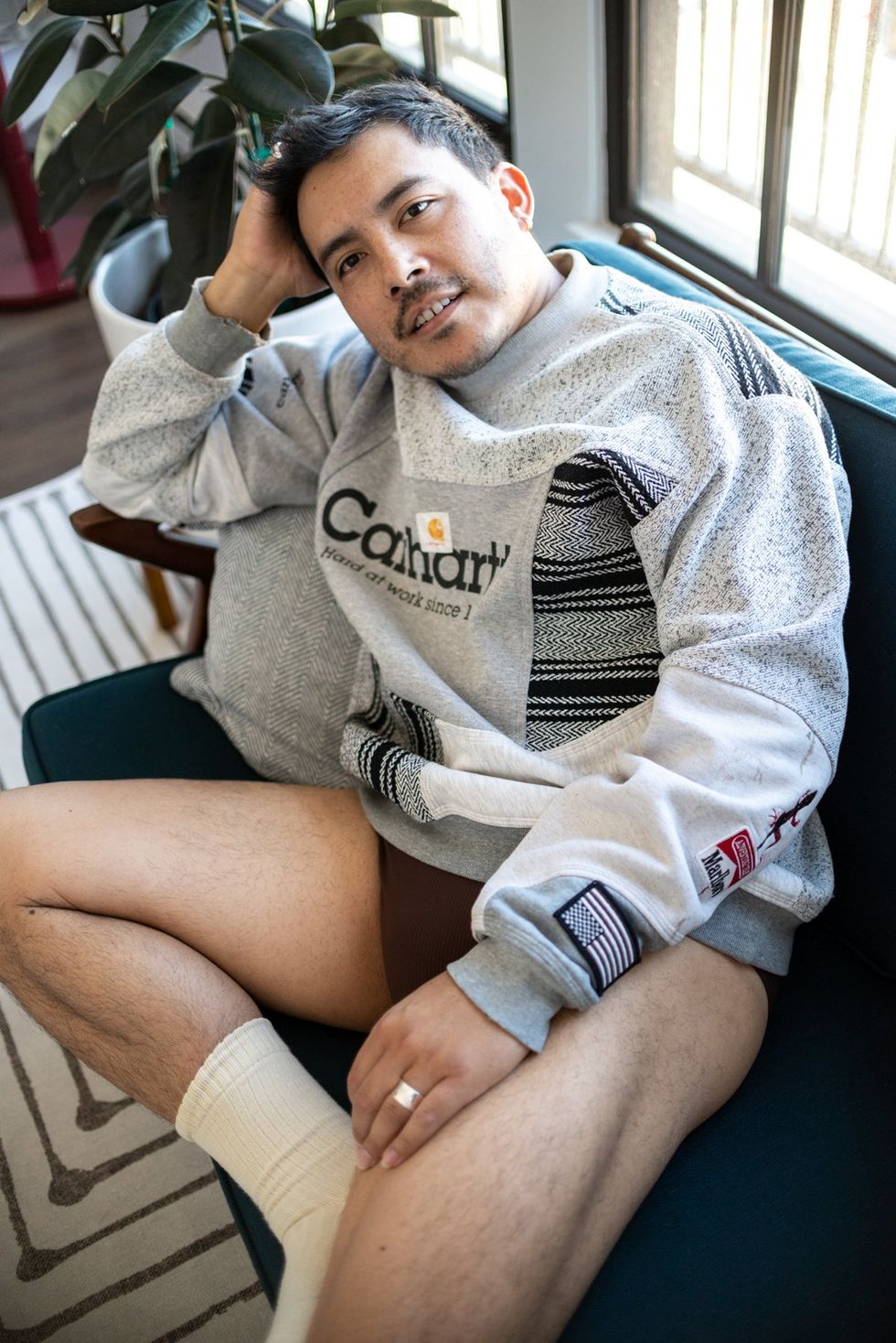 Latinx man sitting in sweatshirt and socks