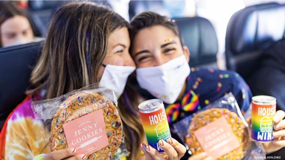 lesbian couple on pride plane showing off their cookies and wine