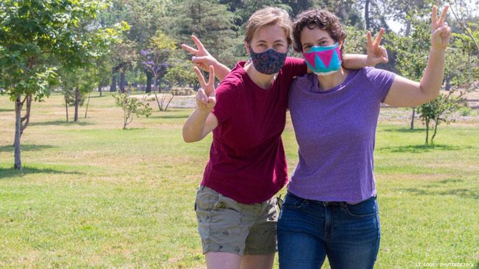 Lesbian couple wearing masks in a park with trees