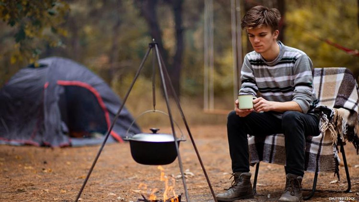 Male Camper Sits by Cooking Fire