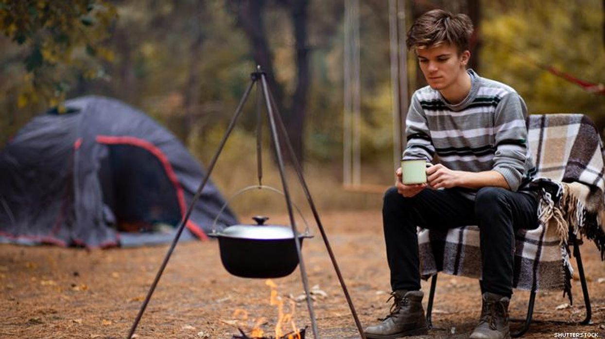 Male Camper Sits by Cooking Fire