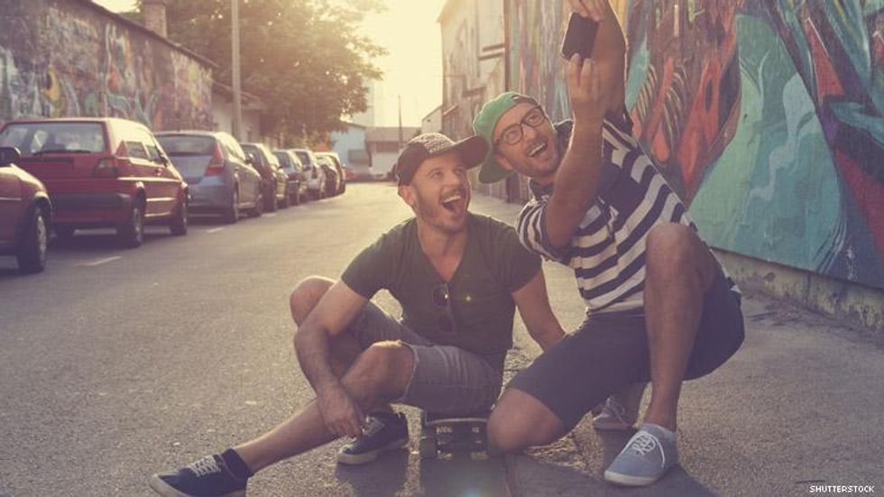 Male couple take selfie in front of graffiti