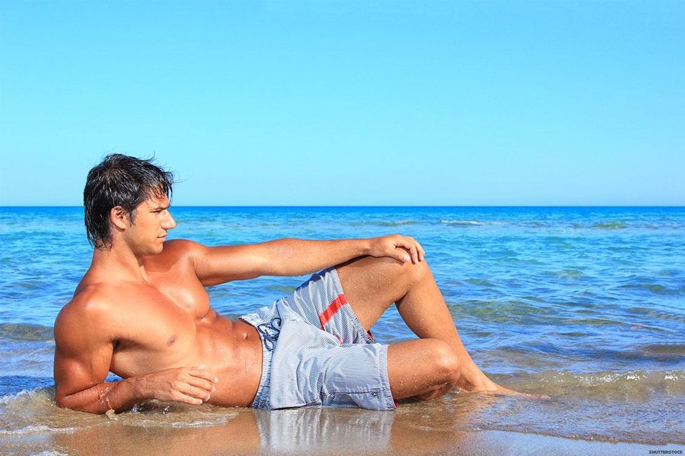Man in swim trunks lying in the water on the beach