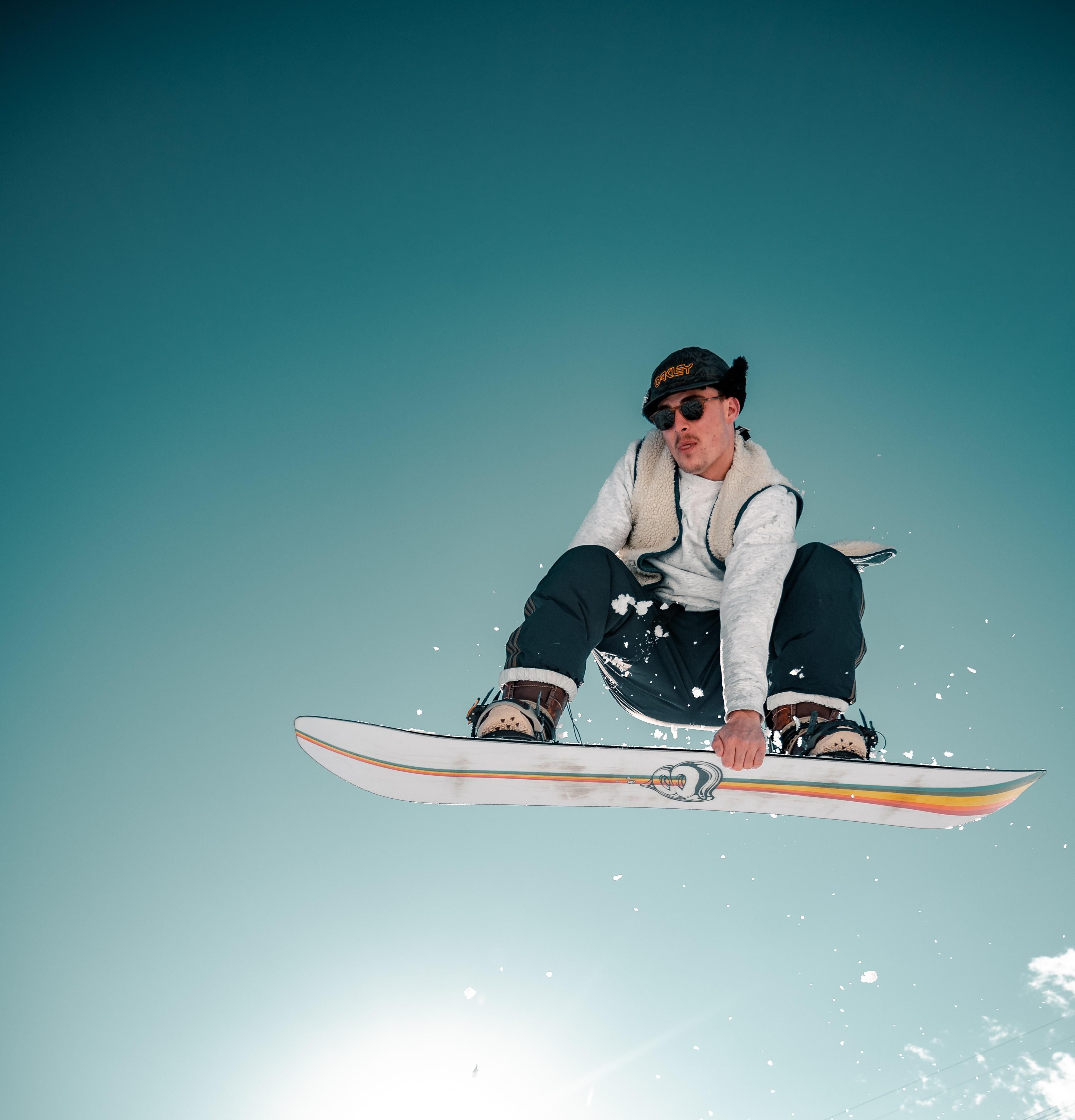 man riding white and rainbow snowboard