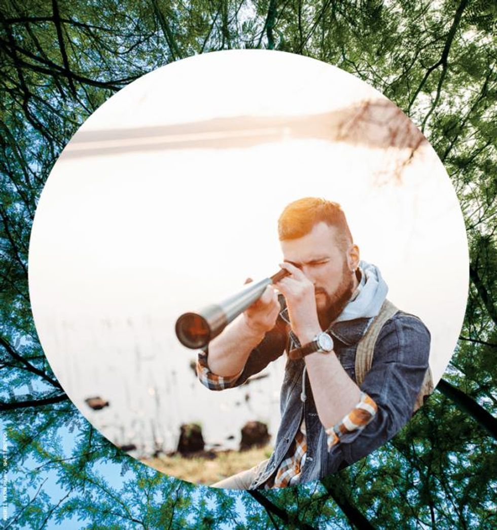 Man using telescope in front of lake