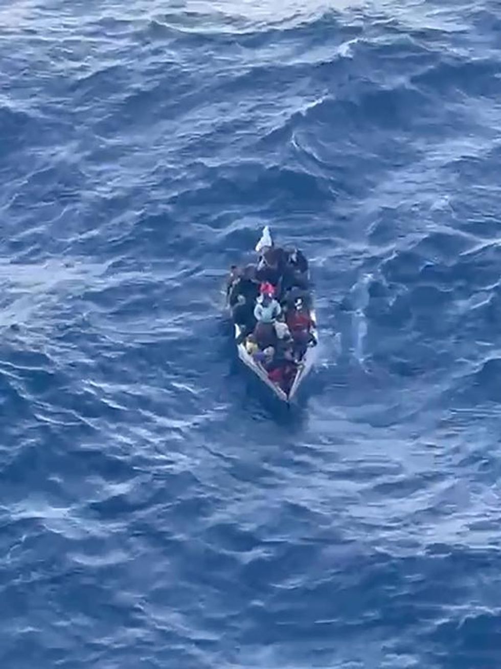 migrants packed into a small boat on the ocean