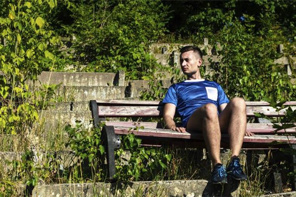Olhe B in soccer uniform sitting on a park bench