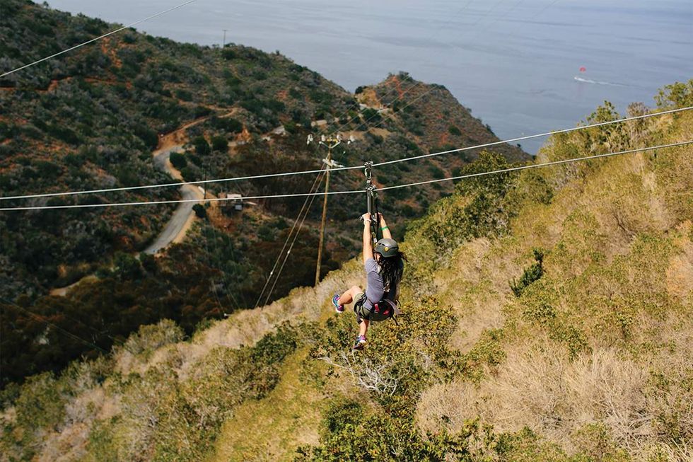 Person ziplining in the canyon, ocean views