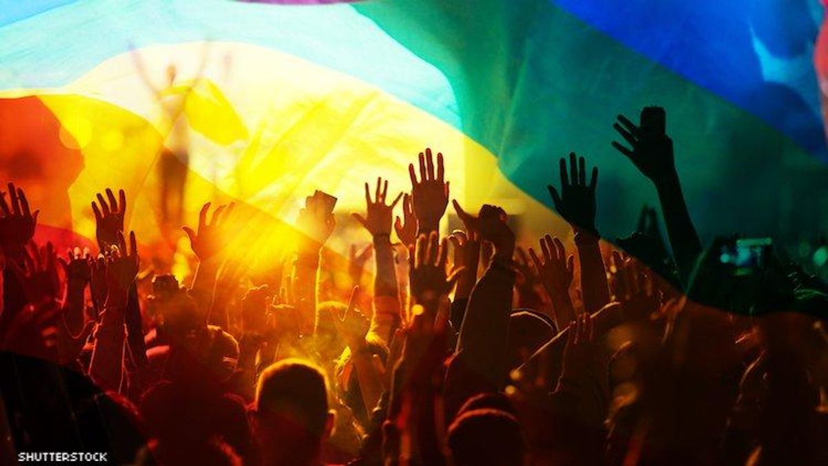 Photo of a group of people with their hands in the air overset with LGBTQ rainbow flag