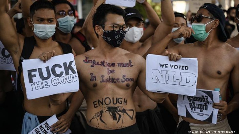 shirtless man holds anti-military slogans
