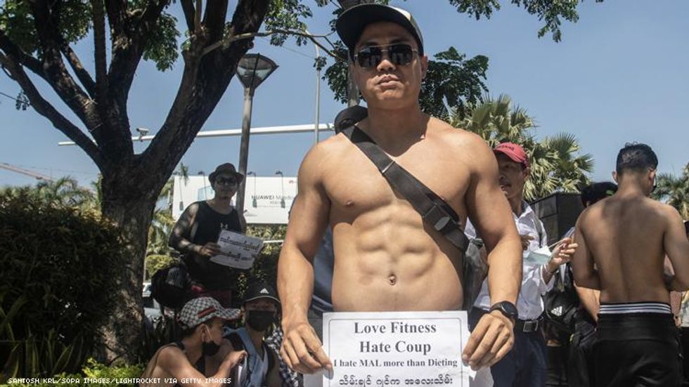 Shirtless man holds sign Love Fitness: Hate Coup in Myanmar