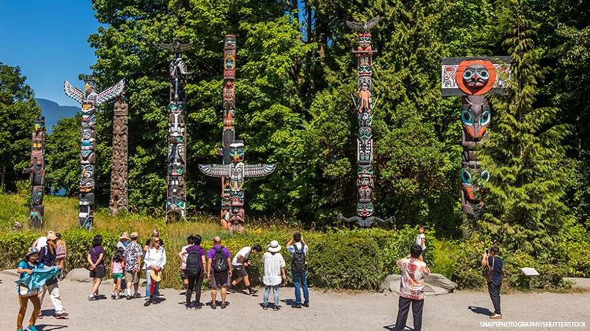 Tourists and explorers before a variety of totem-poles.