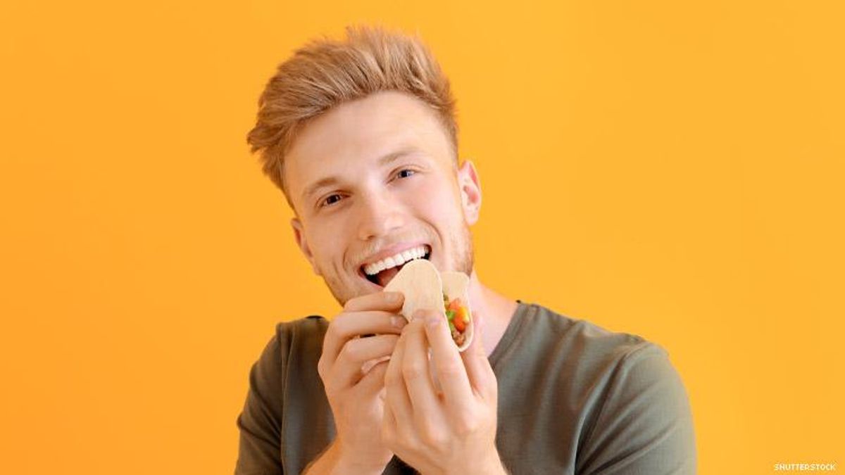 Young white man eating a taco