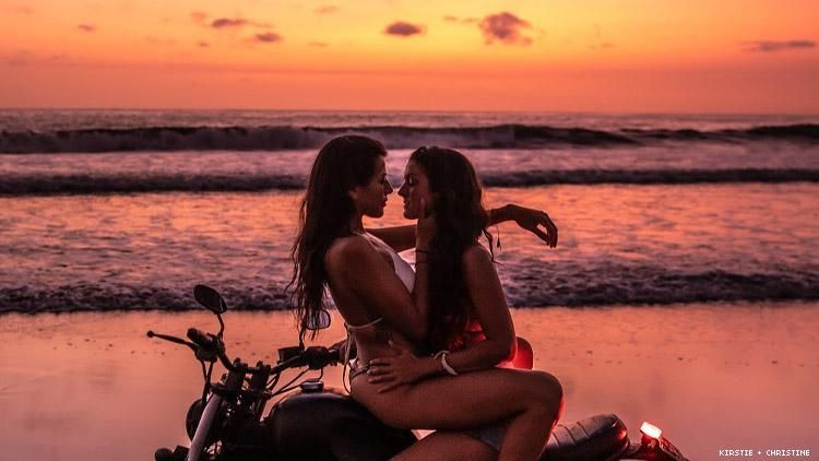 Lesbian couple kissing at sunset on motorcycle on a Bali beach