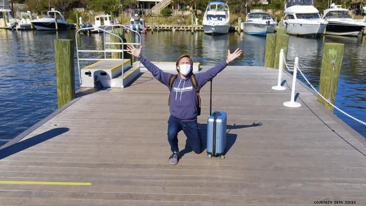 Seth Sikes kneeling a Fire Island dock with arms outstretched