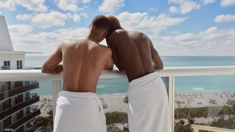 Black gay couple in towels on hotel balcony