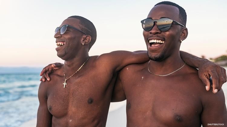 2 Black men with arms around each other's shoulders on a beach