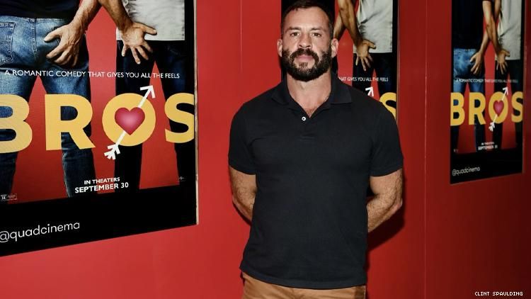 Josh Wood in front of Bros movie posters