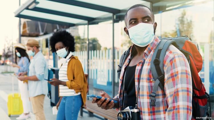 A group of travelers of color social distancing and wearing masks