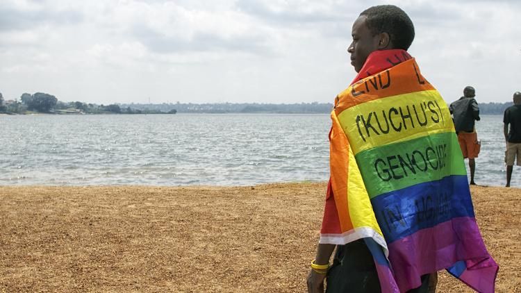 Uganda man on beach wrapped in pride flag