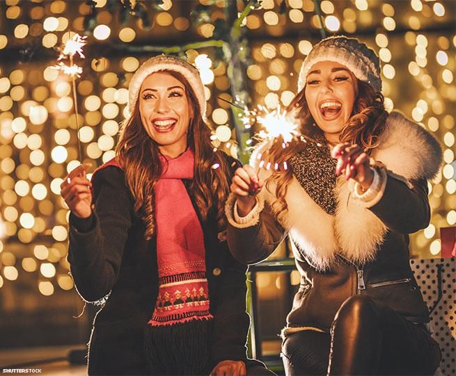 Two women in winter clothing holding sparklers