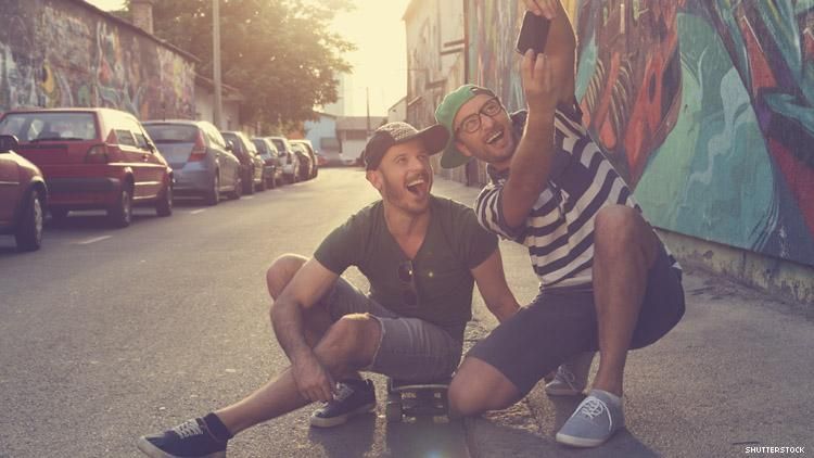 Male couple take selfie in front of graffiti 