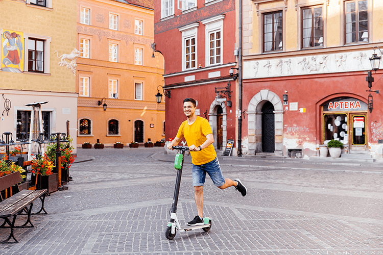 Man riding a scooter through the streets of Warsaw