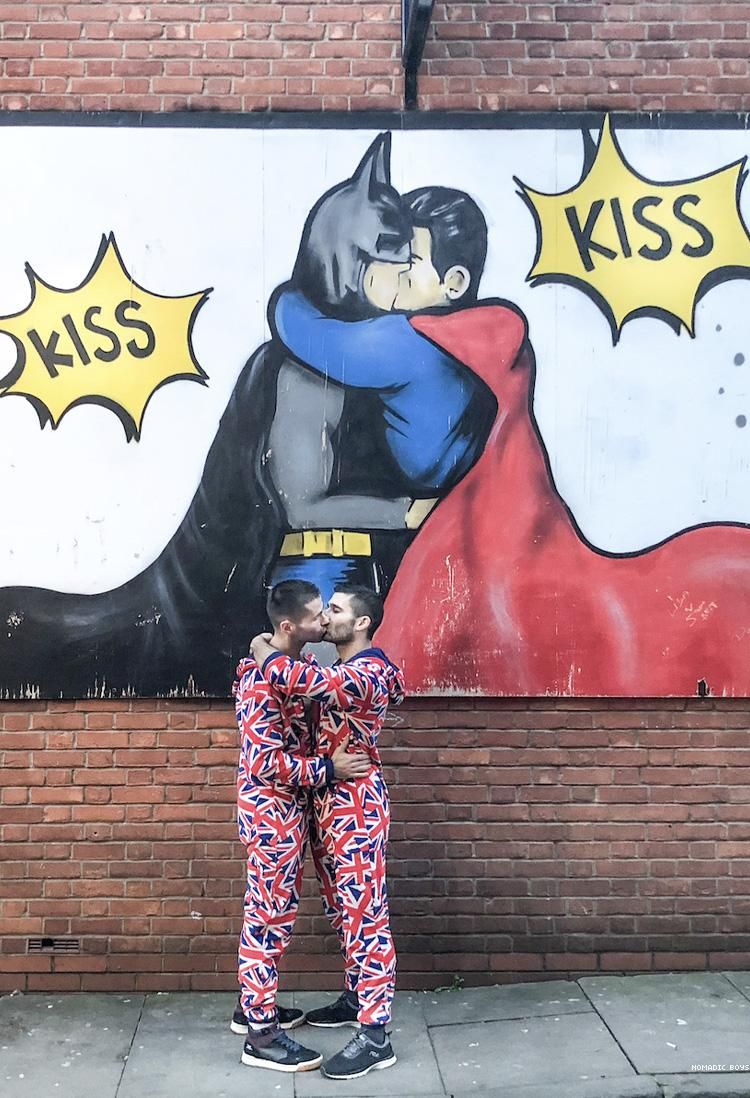 Nomadic Boys kissing in front of a mural of Batman and Superman kissing in Manchester UK 